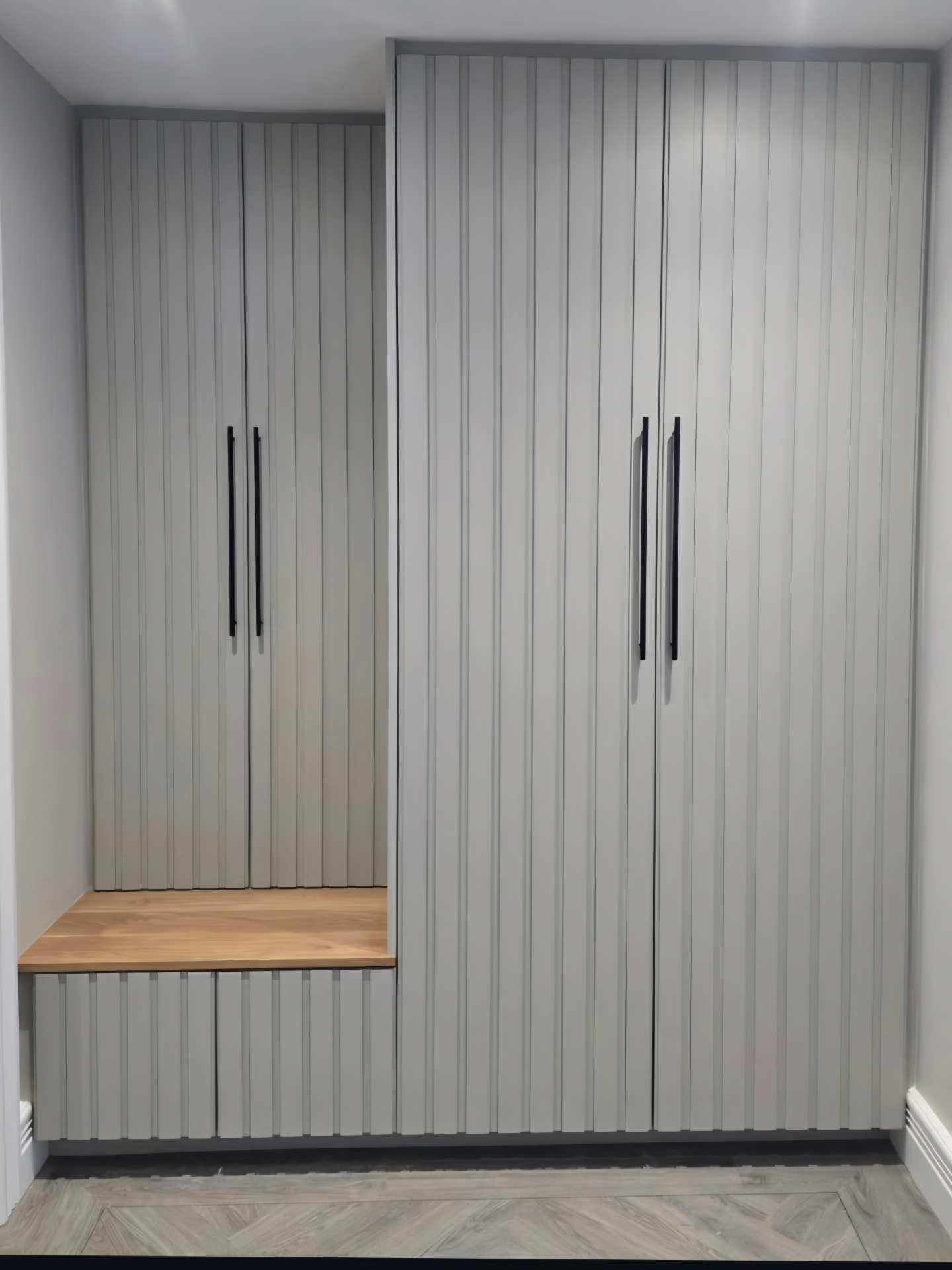 Contemporary floor-to-ceiling slatted wardrobe doors painted in a soft grey finish