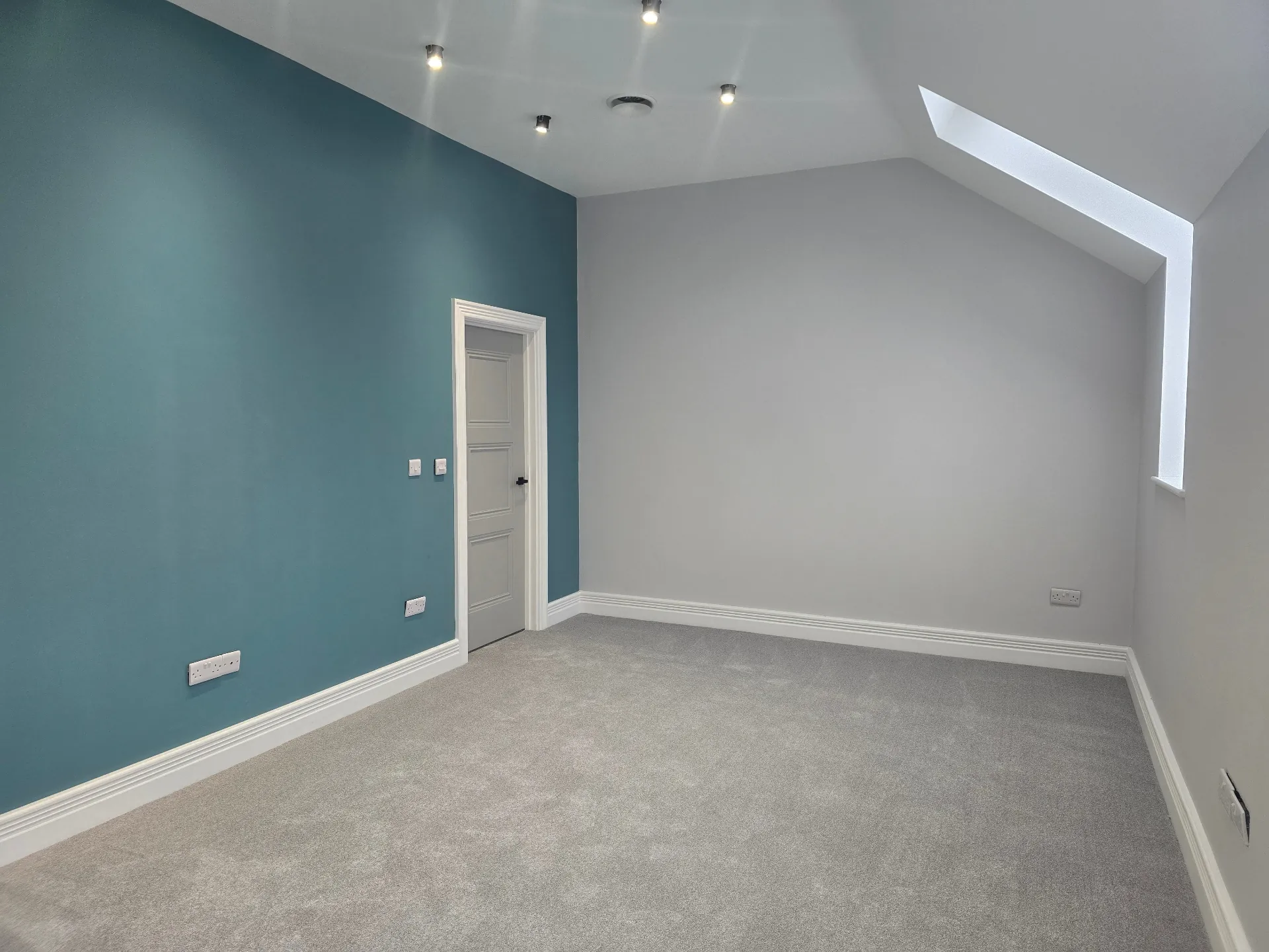 Interior room renovation showing a freshly painted deep teal feature wall and light grey flooring