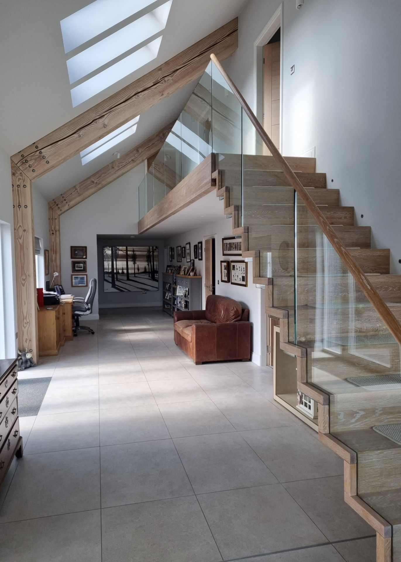 Large open-plan hallway with timber framing and glass balustrade repainted in Melton Mowbray, Leicestershire