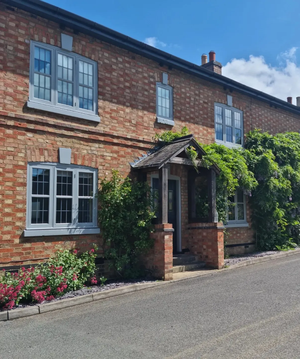 Traditional red brick cottage exterior with newly painted grey window frames and matching front porch