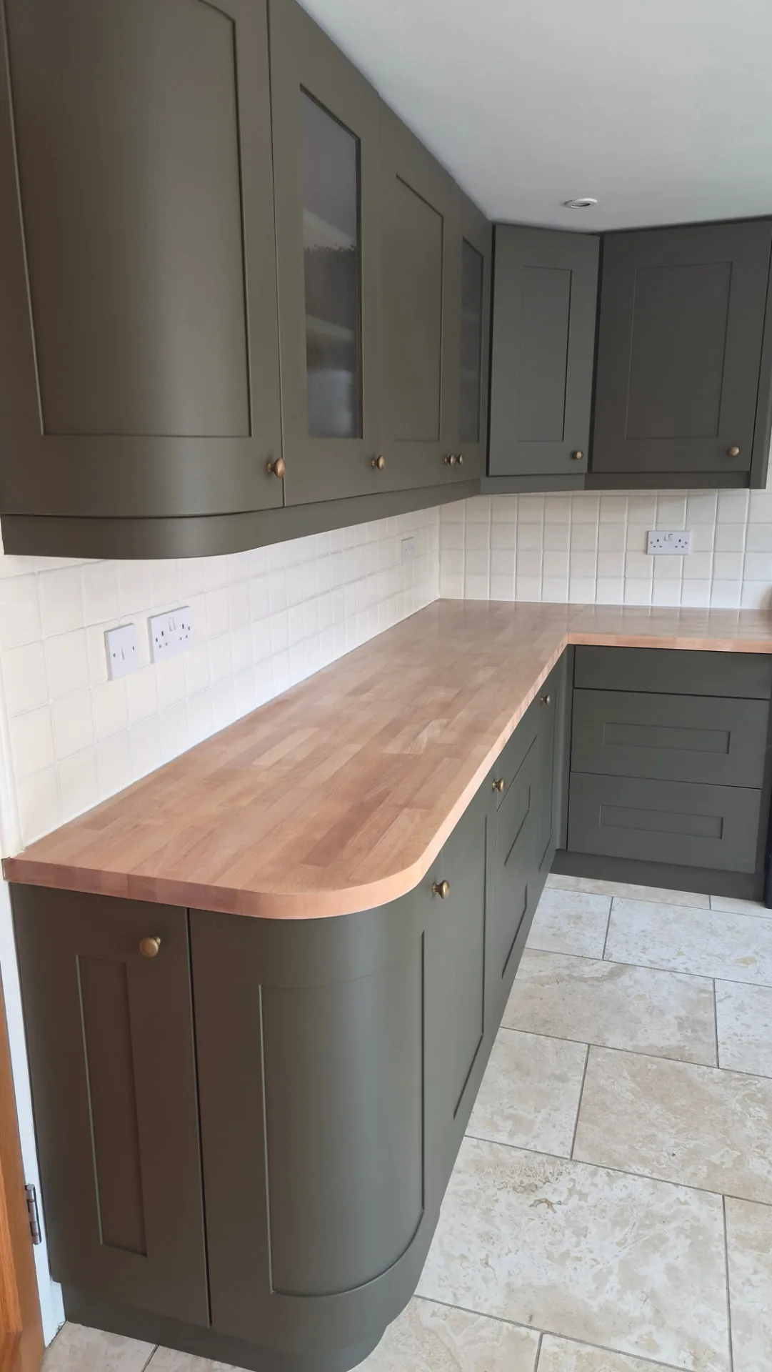 Same kitchen resprayed in a dark olive green shaker finish with brass hardware, Leicestershire